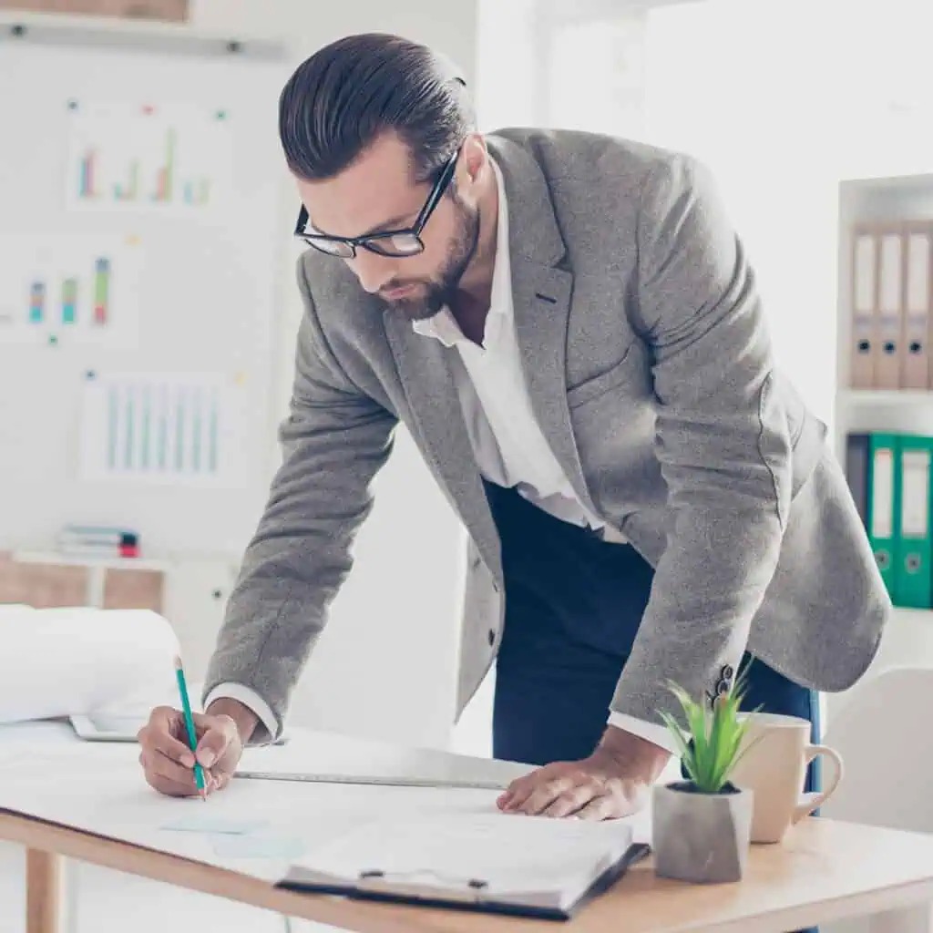 designer in formal wear and glasses draws a diagram on paper