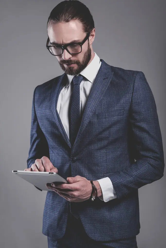 Portrait of a businessman dressed in elegant blue suit with glasses using touchpad