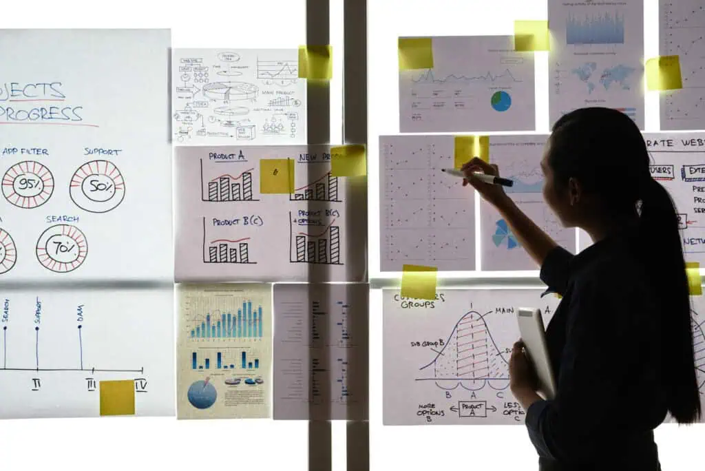Business woman analyzing charts and graphs hanging on the wall