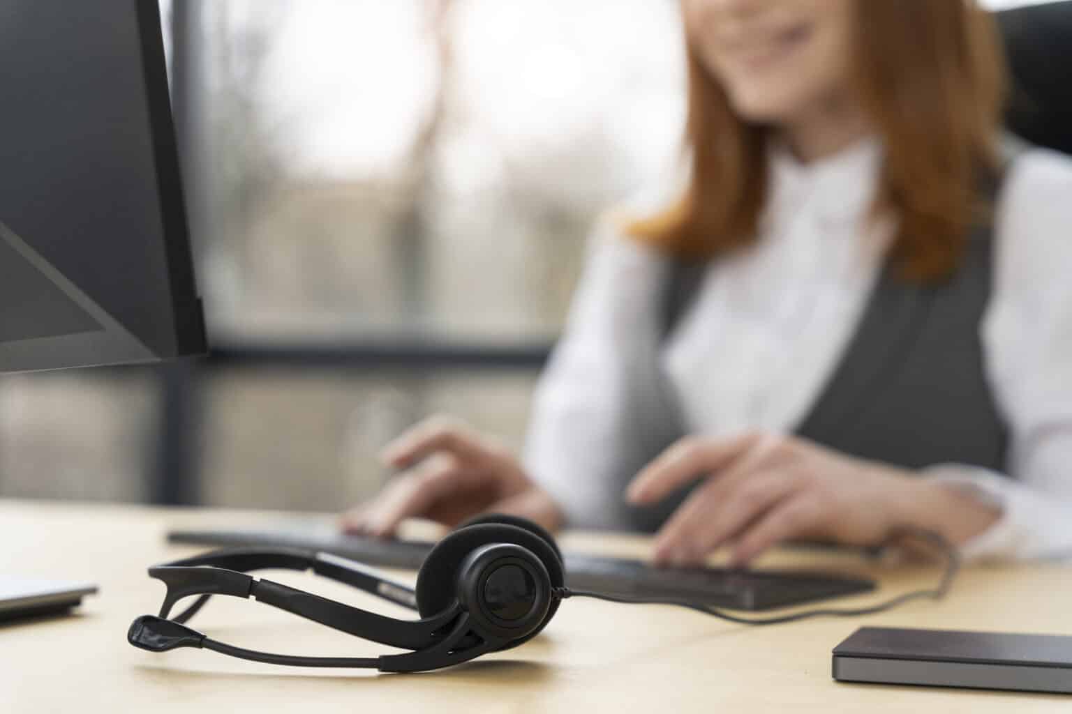 Customer service expert working on computer with her headset on the table